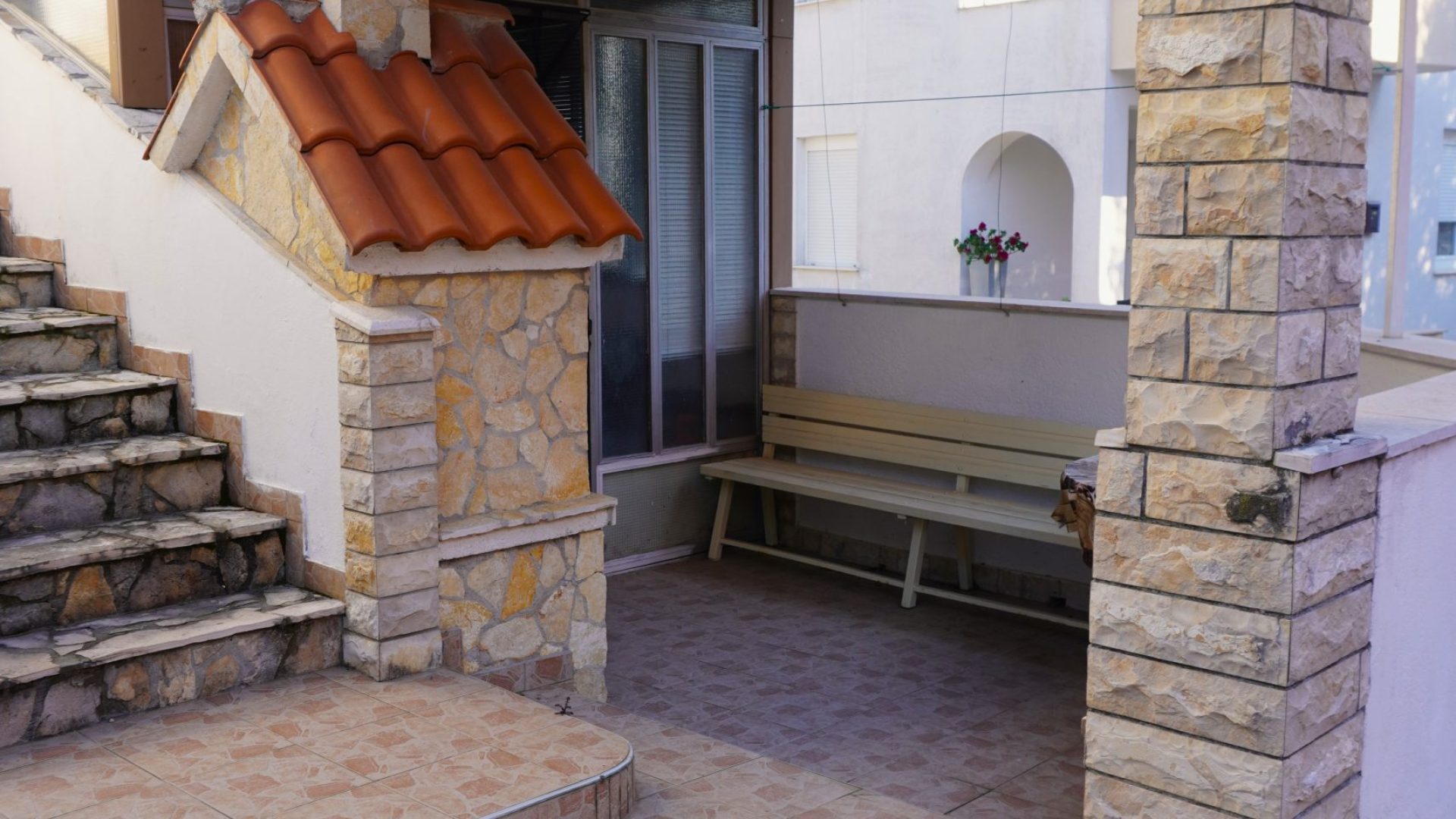 Natkriveni ulaz i kamene stepenice apartmanske kuće u Vodicama