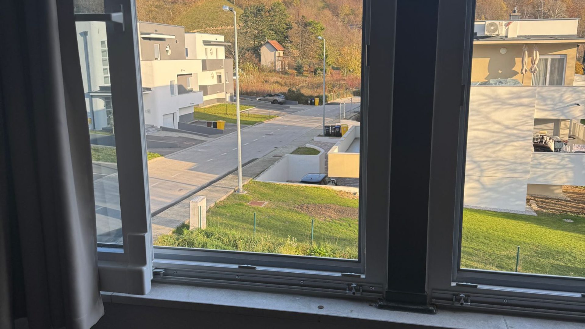Pogled kroz prozor na moderne kuće i zelenilo u Gračanima.