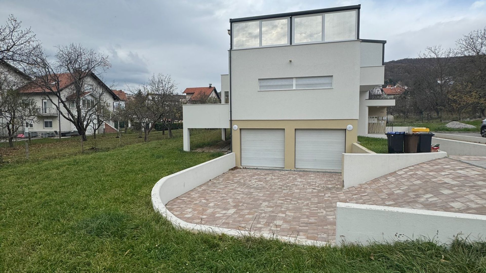 Moderna urbana vila s dvije garaže i uređenim okolišem.